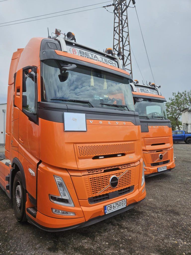 Два оранжеви камиона Volvo, готови за товарене и сухопътен транспорт в Европа